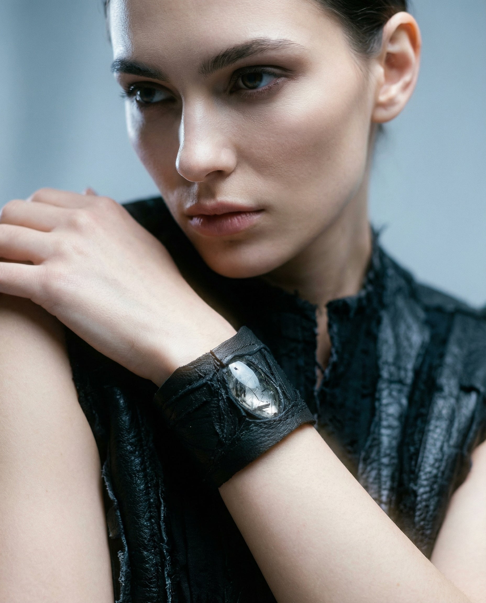 Woman wearing a black wristband with a reflective element against a neutral background